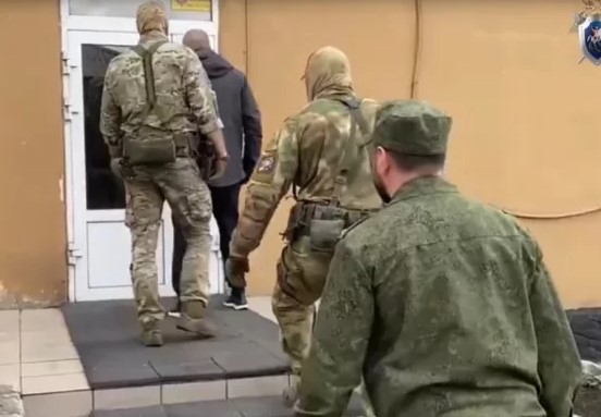 Силовики в масках проводят обыск в кабинете чиновника администрации, на столе разложены папки с документами
