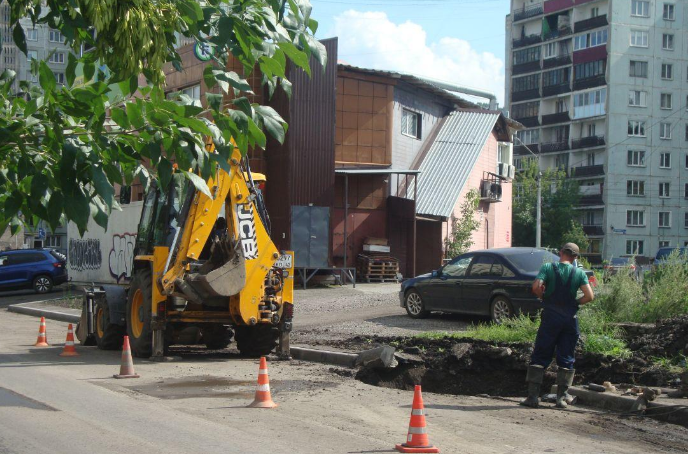 Экскаватор Водоканала на раскопанном участке нового асфальта в Новокузнецке