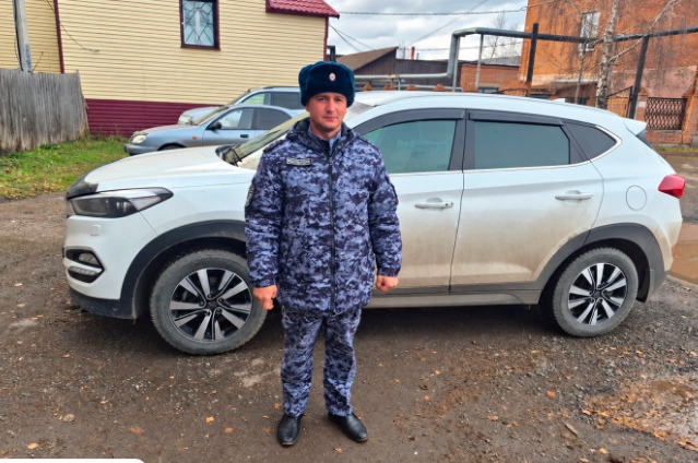 Капитан полиции Василий Л. на фоне служебного автомобиля Росгвардии